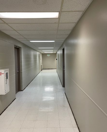 A newly painted office hallway featuring smooth, light-colored walls, bright overhead lighting, and clean flooring, creating a fresh and professional look.