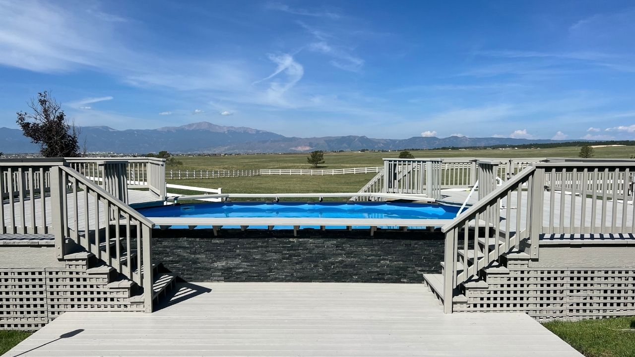 A newly painted deck surrounding pool with mountain view and clear blue sky