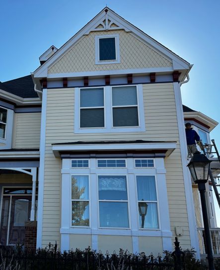 A street view under a vibrant blue sky features a beautifully painted home by Elk Horn Painting. The white - beige exterior shines with a fresh, professional finish.