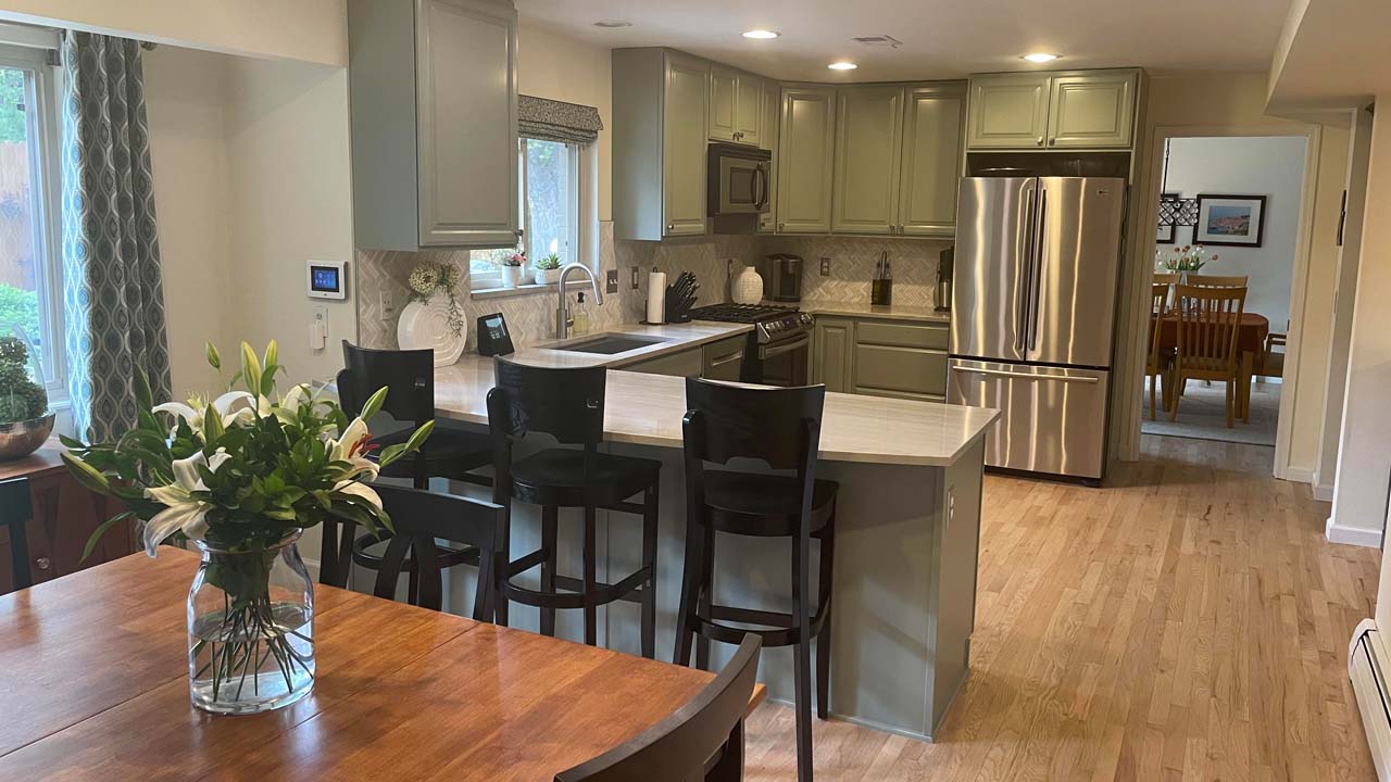 This photo is an example of work that interior panters do. Cabinet repainting and a view of a newly painted kitchen and kitchen island.