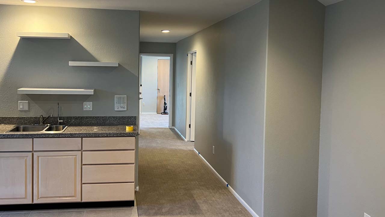 Residential interior looking down a newly painted hall with a kitchen area to the left with newly painted cabinets.