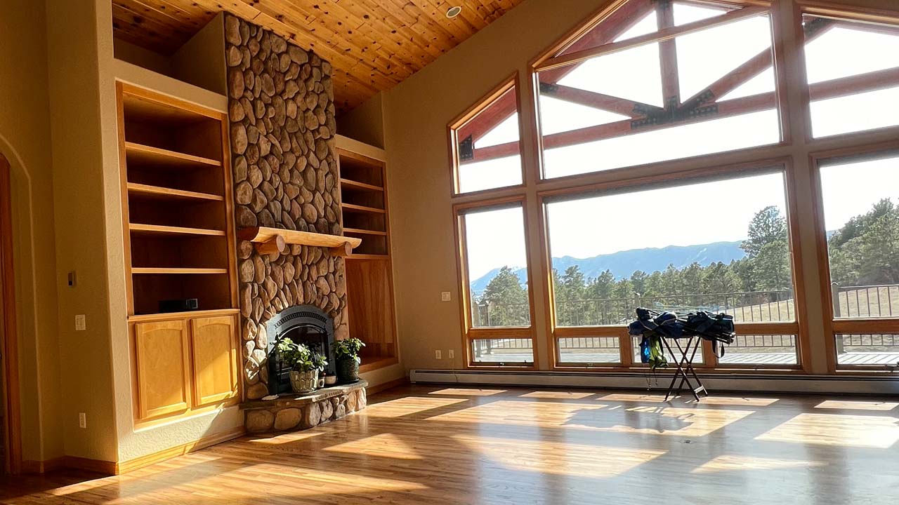 Interior photo of a painting contractors job. Hardwood flooring and wall of glass windows. Bright sun coming in the windows.