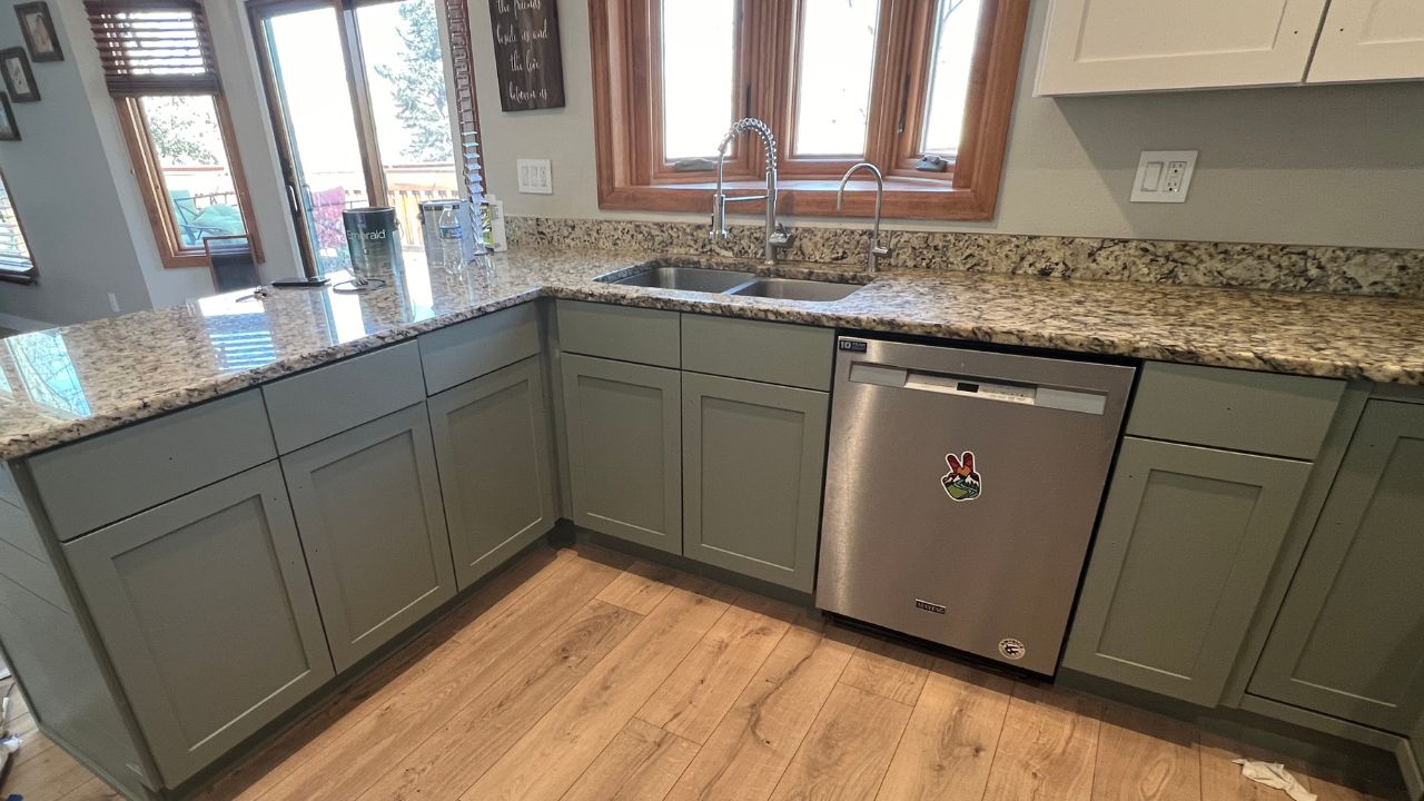 A modern kitchen featuring newly painted cabinets in a sleek, fresh green finish by Elk Horn Painting.