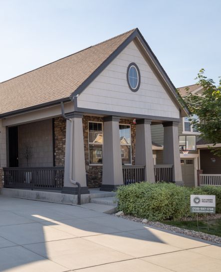 A street view under a vibrant blue sky features a beautifully painted home by Elk Horn Painting. The beige exterior shines with a fresh, professional finish.