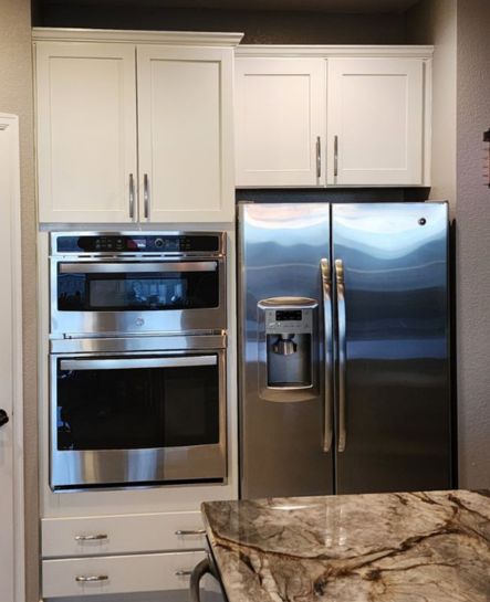 A clean and elegant kitchen cabinet painting project by Elk Horn Painting, featuring crisp white cabinetry paired with stainless steel appliances.