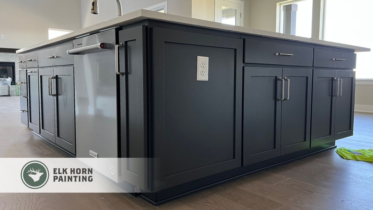 A close-up view of a modern kitchen island freshly painted in deep charcoal by Elk Horn Painting, highlighting detailed cabinet work.