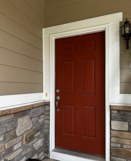 Brick red front door of a home that has been recently repainted.