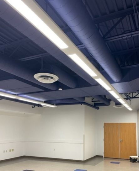 An interior commercial ceiling space with exposed ductwork painted in deep blue by Elk Horn Painting – Denver, giving the area a bold, modern finish.