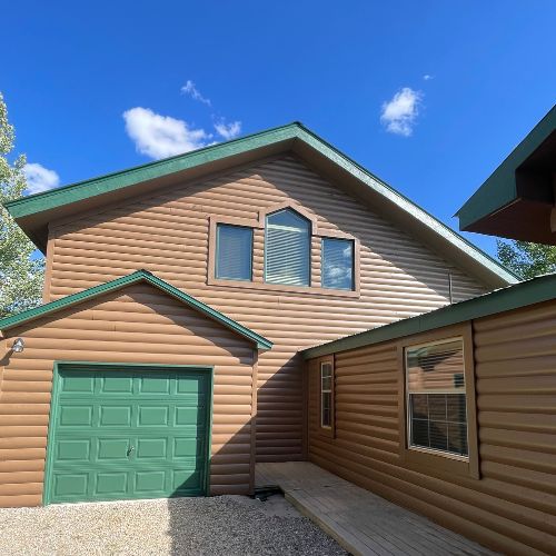 Painting Companies - Elk Horn Painting - Denver This image showcases a log-style home with a fresh brown and green exterior repaint by Elk Horn Painting – Denver, enhancing its rustic charm.