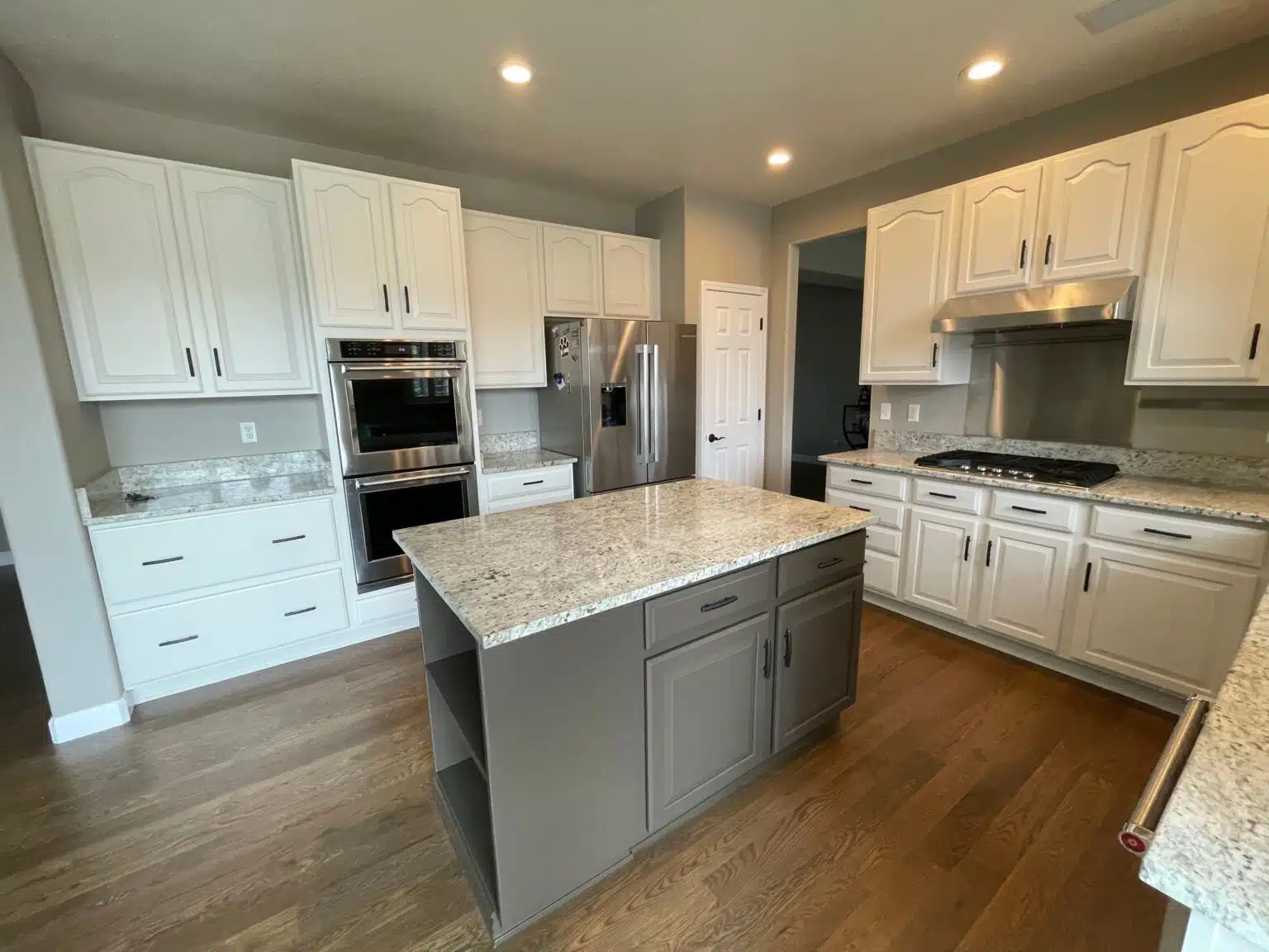 White cabinets and a gray-painted island near wall ovens, cabinet painting by Elk Horn Painting for Ponderosa Park